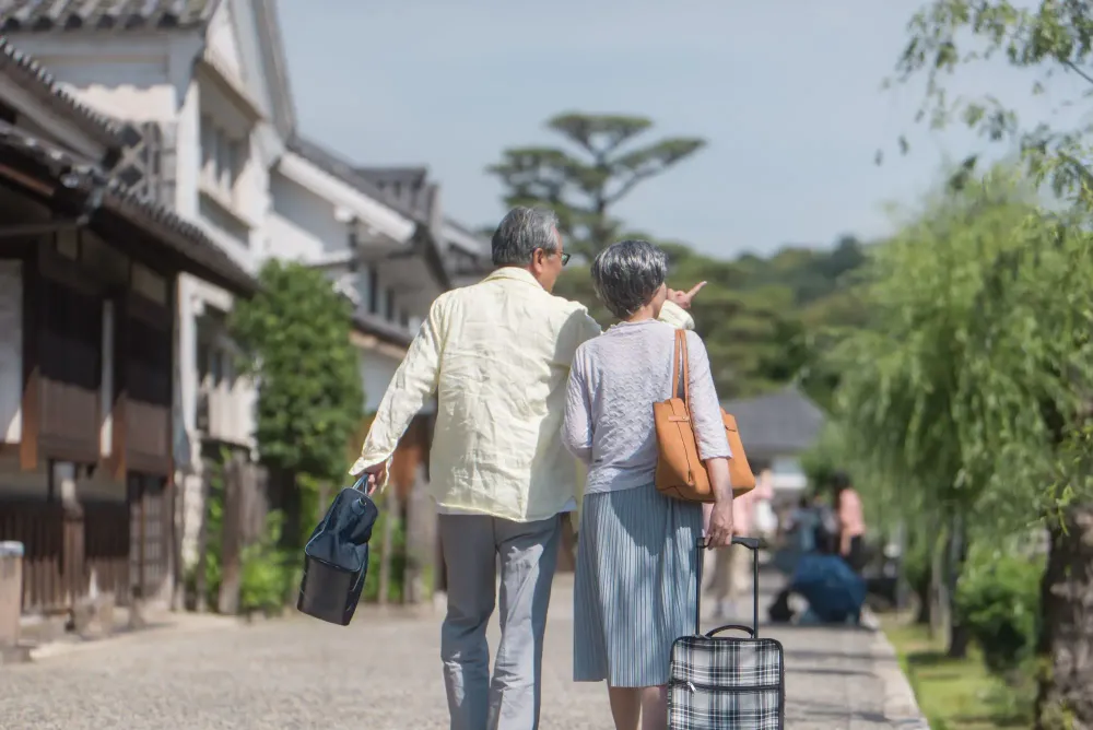 A couple carrying luggage and walking through a scenic destination